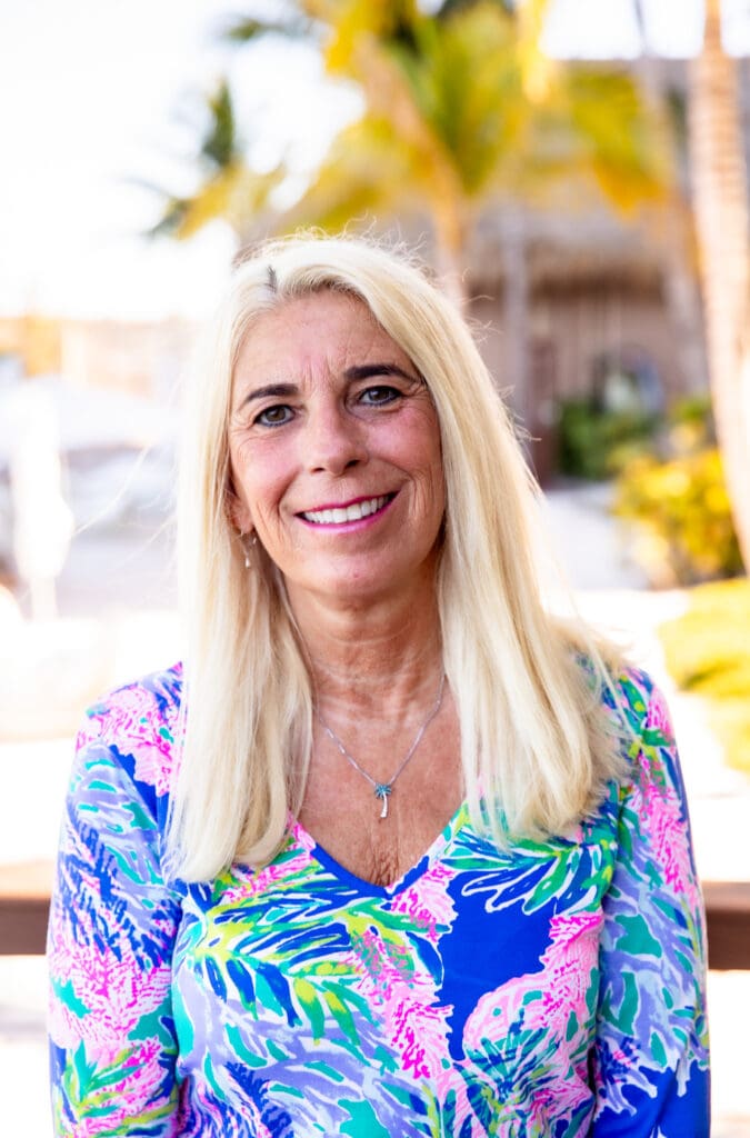 Smiling woman with blonde hair in a floral blouse.