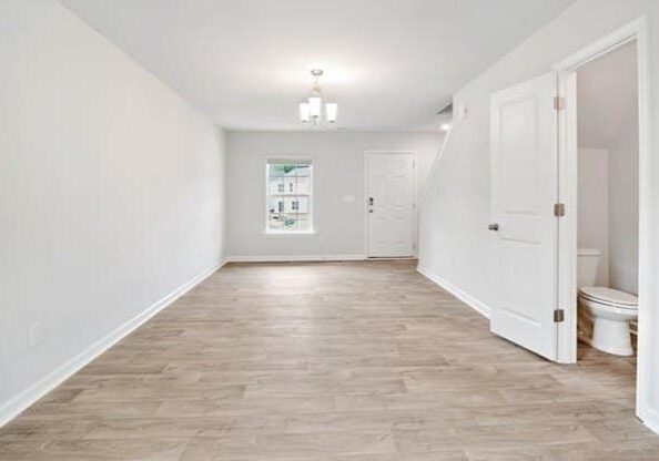 A white room with wood floors and a window.