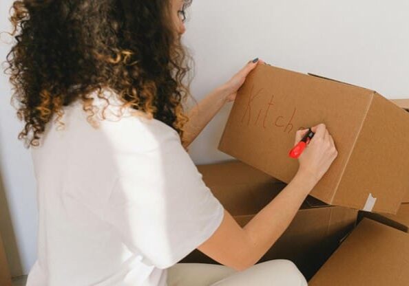 Person writing on a cardboard box with a red marker.